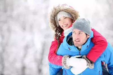 A playful couple enjoying a wintry walk in the woods.