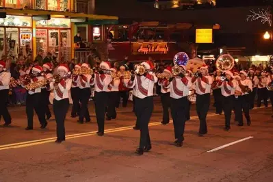 A marching band with Santa hats performing at the Fantasy of Lights Christmas Parade in Gatlinburg.