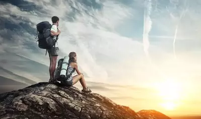 Two backpackers standing at the top of a mountain in the Smokies looking at the view
