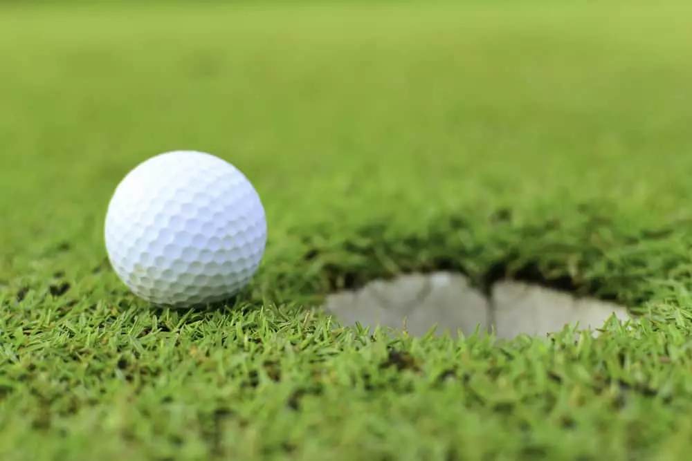 golf ball next to hole