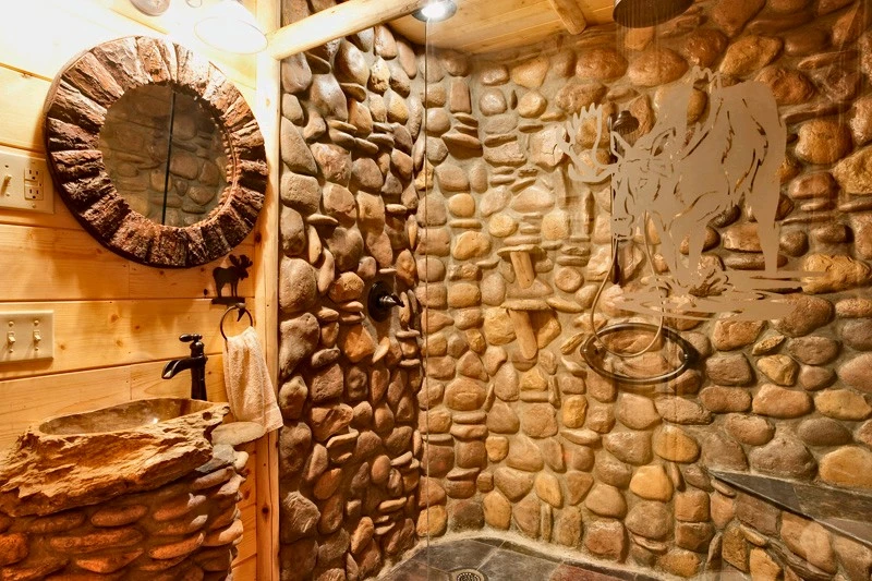 Elegant bathroom in the "Wolf Room" with a large rock shower and glass doors