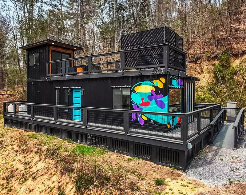 outside view of black container home with graffitti