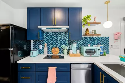 front view of kitchen with blue cabinets, cooktop and retro appliances