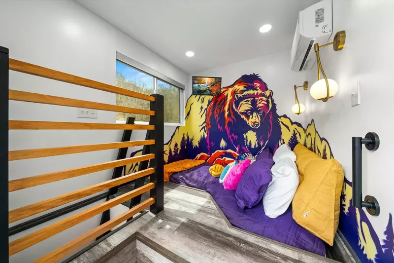 bedroom loft with cut out sunken bed, bear graffiti wall, sconces and tv