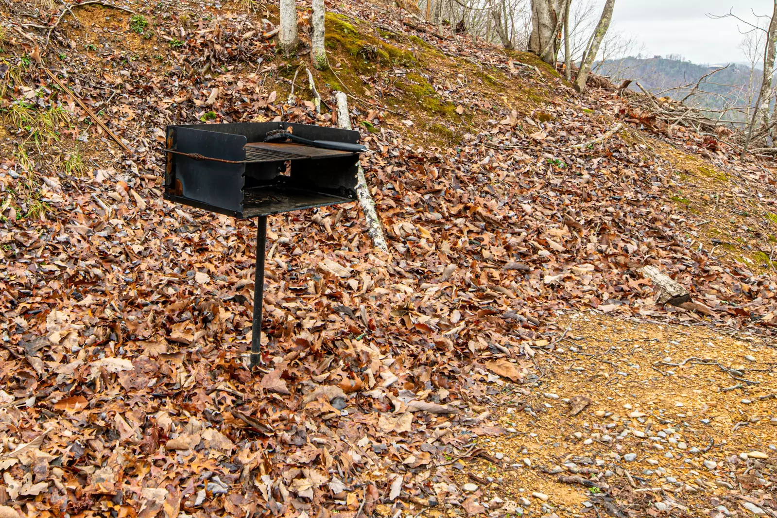 Park style (charcoal) grill next to gravel drive